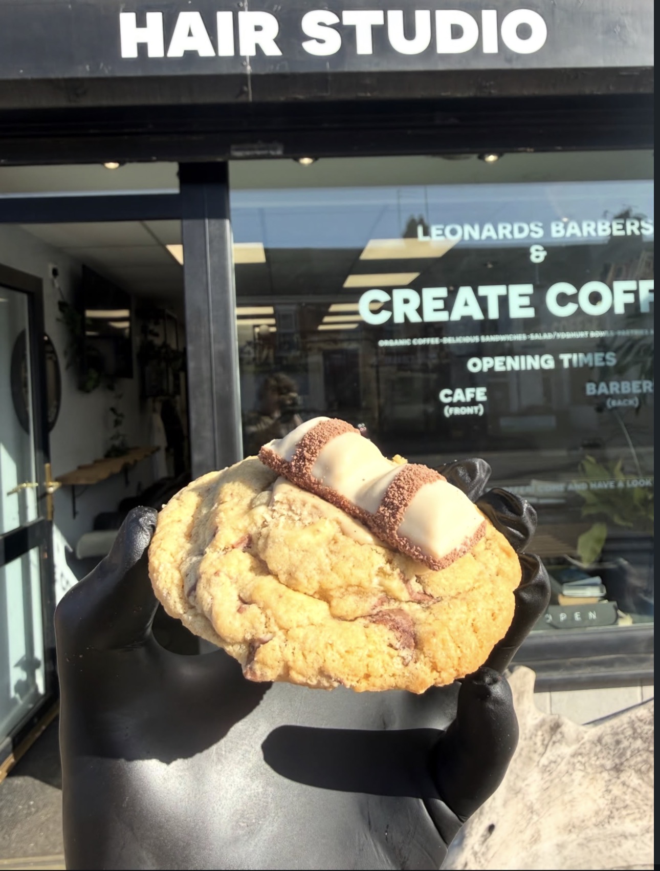A chocolate-topped cookie held outside Create Coffee